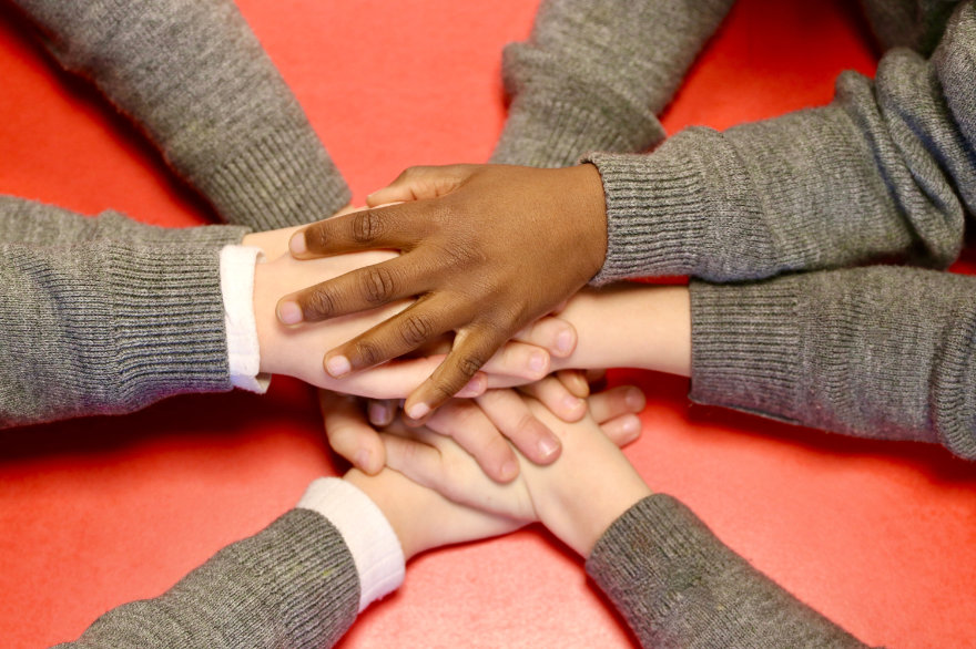 Kinderhände verschiedener Ethnien liegen übereinander.